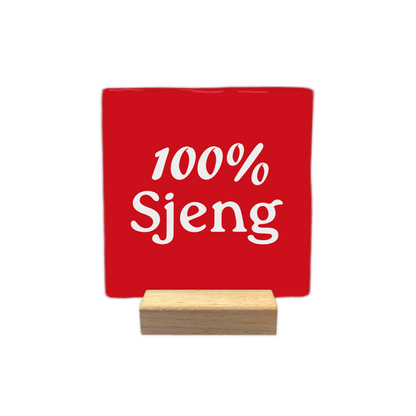 100% Sjeng - Decoratie tegel - Formaat: - Op deze decoratie tegel staat de witte tekst "100% Sjeng" centraal afgebeeld tegen een rode achtergrond. Het ontwerp is strak en minimalistisch van vorm. - Snelwenskaart