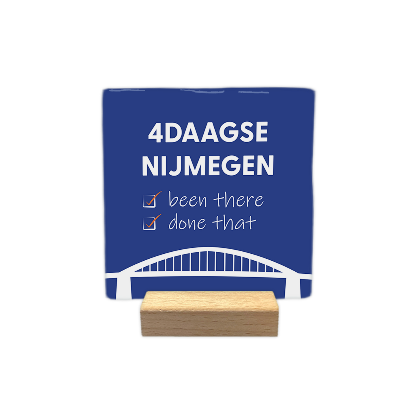 4daagse Nijmegen - Decoratie tegel - Formaat: - Op deze decoratie tegel staat bovenaan de tekst "4daagse Nijmegen" in witte hoofdletters. Daaronder staan twee regels met de tekst "been there" en "done that", waarbij voor elke regel een wit selectievakje met een oranje vinkje is geplaatst. Onderaan het ontwerp is een gestileerde witte afbeelding van een brug zichtbaar. Het geheel is geplaatst op een donkerblauwe achtergrond. - Snelwenskaart