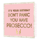 It's your birthday don't panic you have prosecco! - Formaat: Standaard - Vorm: Vierkant - Verjaardagskaart - Op deze kaart staat de tekst 'It's your birthday don't panic you have prosecco!' in het goud met een schaduw erachter. Onder de tekst staan twee gouden champagne flessen. De tekst en flessen staan in een roze vierkant. Buitenom het vierkant is een witte achtergrond met gouden stippen. - Snelwenskaart