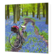 Fiets - Formaat: Groot - Vorm: Vierkant - Blanco kaart - Op deze wenskaart staat een foto van een fiets die in het bos staat tussen blauwe bloemen. - Snelwenskaart