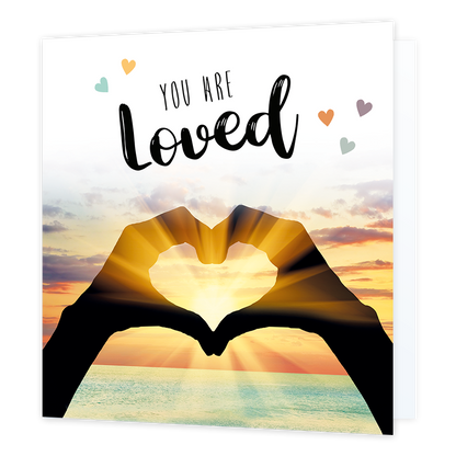 You are loved - Formaat: Normaal - Vorm: Vierkant - Liefdeskaart - Op deze wenskaart staat de zee met op de voorgrond twee handen die een hartje vormen waar de zon doorheen schijnt. In de illustratie staat de tekst: "You are loved". - Snelwenskaart
