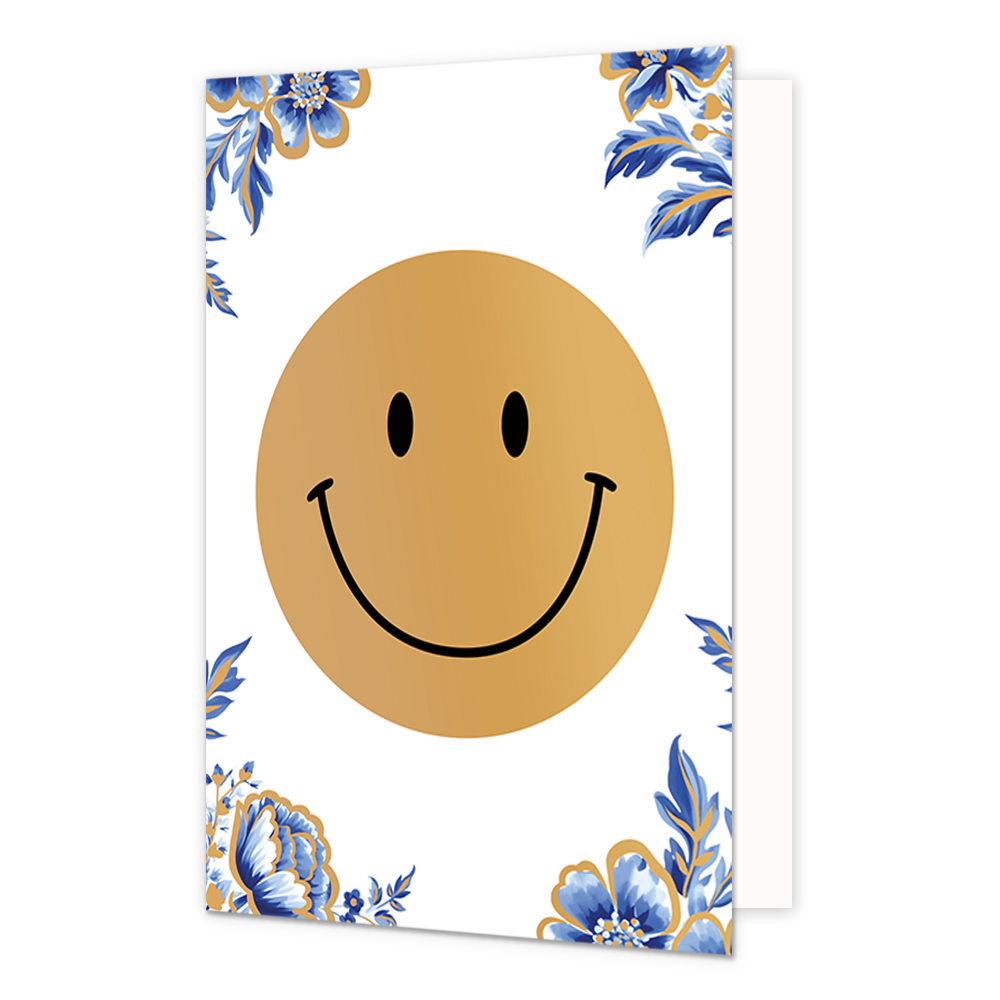Smiley - Formaat: Normaal - Vorm: Staand - Blanco kaart - Op deze wenskaart staat centraal een grote, goudkleurige smiley afgebeeld met een zwarte glimlach en zwarte ogen. De hoeken van de kaart zijn gedecoreerd met blauw-witte bloemen en bladeren in de stijl van Delfts blauw, die zijn afgewerkt met fijne gouden randen. De achtergrond van de gehele illustratie is effen wit. - Snelwenskaart