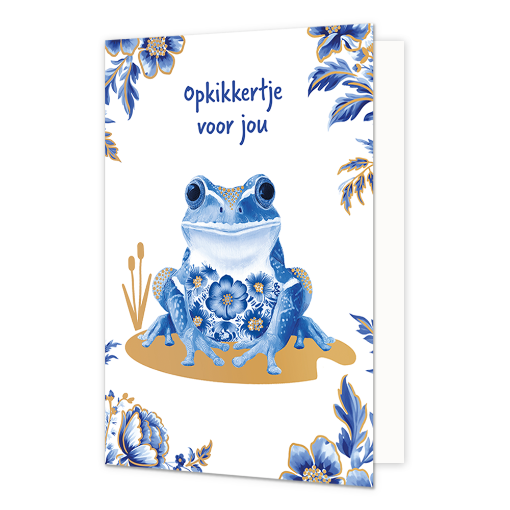 Opkikkertje voor jou - Formaat: Normaal - Vorm: Staand - Opkikker kaart - Op deze wenskaart staat centraal een kikker afgebeeld die is gedecoreerd met blauw-witte bloemmotieven in Delfts blauwe stijl en goudkleurige stippen op de poten en rug. De kikker zit op een goudkleurig vlak met daarnaast twee goudkleurige rietstengels, terwijl de hoeken van de kaart zijn versierd met bijpassende blauwe bloemen en bladeren met gouden randen tegen een witte achtergrond. Bovenaan de illustratie staat in blauwe, handges