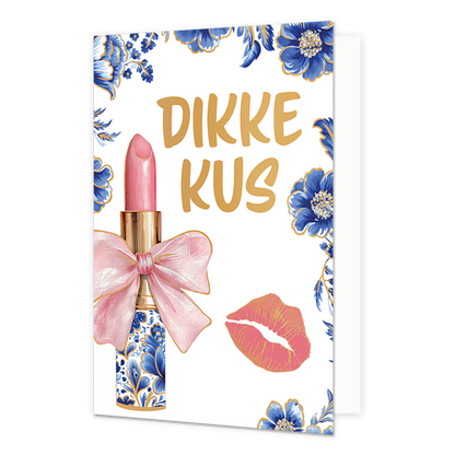 Op deze wenskaart staat aan de linkerzijde een huls lippenstift afgebeeld, waarvan de houder is gedecoreerd met blauw-witte bloemmotieven in Delfts blauwe stijl en de roze lippenstift is omhuld door een grote roze strik met gouden randen. Rechtsonder bevindt zich een roze kusafdruk, terwijl de randen en hoeken van de kaart zijn versierd met bijpassende blauwe bloemen en bladeren met gouden accenten tegen een witte achtergrond. Rechtsboven staat in gouden, handgeschreven letters de tekst "Dikke kus".