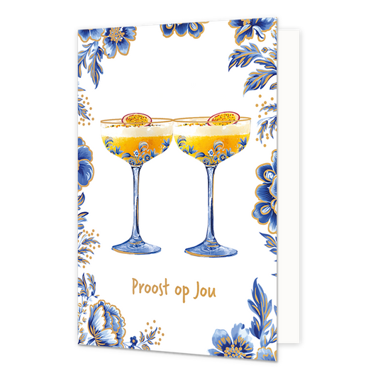 Proost op jou - Formaat: Normaal - Vorm: Staand - Proost kaart - Op deze wenskaart staan centraal twee cocktailglazen gevuld met een gele drank en een witte schuimlaag, die elk zijn gegarneerd met een halve passievrucht. De glazen zelf en de randen van de kaart zijn versierd met blauw-witte bloemmotieven in Delfts blauwe stijl en voorzien van fijne goudkleurige accenten. De gehele illustratie is geplaatst tegen een effen witte achtergrond. Onderaan de glazen staat in goudkleurige, handgeschreven letters de