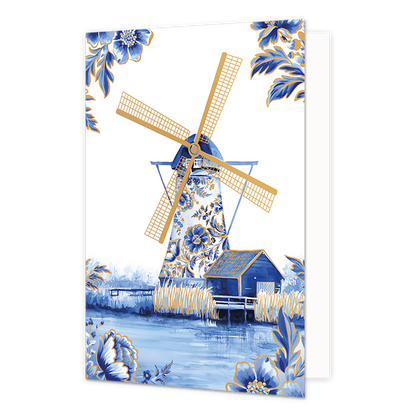 Molen - Formaat: Normaal - Vorm: Staand - Blanco kaart - Op deze wenskaart staat centraal een traditionele windmolen afgebeeld, waarvan de romp volledig is versierd met blauw-witte bloemmotieven in Delfts blauwe stijl en goudkleurige wieken heeft. Naast de molen staat een klein blauw schuurtje met een goudkleurig dak aan de waterkant, omringd door goudkleurige rietstengels en een weerspiegeling in het water op de voorgrond. De hoeken van de kaart zijn op een witte achtergrond gedecoreerd met bijpassende gr