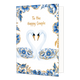 To the happy couple - Formaat: Normaal - Vorm: Staand - Huwelijkskaart - Op deze wenskaart staan centraal twee zwanen tegenover elkaar afgebeeld die met hun halzen een hartvorm vormen, waarbij hun vleugels gedecoreerd zijn met blauw-witte bloemmotieven in Delfts blauwe stijl en goudkleurige stippen. De snavels van de zwanen zijn goudkleurig met zwart, en de randen en hoeken van de kaart zijn rijkelijk versierd met bijpassende blauwe bloemen en bladeren met gouden accenten tegen een witte achtergrond. Boven