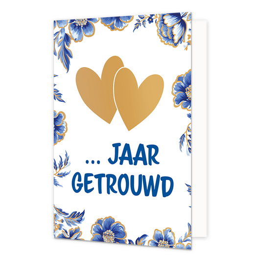 ... Jaar getrouwd - Formaat: Normaal - Vorm: Staand - Jubileumkaart - Op deze wenskaart staan centraal twee goudkleurige harten afgebeeld die elkaar deels overlappen tegen een effen witte achtergrond. De randen en hoeken van de kaart zijn rijkelijk versierd met blauw-witte bloemen en bladeren in Delfts blauwe stijl, voorzien van fijne goudkleurige accenten. Onder de harten staat in grote, blauwe letters de tekst "... Jaar Getrouwd" geschreven. - Snelwenskaart