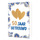 50 jaar getrouwd - Formaat: Standaard - Vorm: Staand - Jubileumkaart - Op deze wenskaart staan centraal twee goudkleurige harten afgebeeld die elkaar deels overlappen tegen een effen witte achtergrond. De randen en hoeken van de kaart zijn rijkelijk versierd met blauw-witte bloemen en bladeren in Delfts blauwe stijl, voorzien van goudkleurige accenten. Onder de harten staat de tekst "50 Jaar Getrouwd" geschreven, waarbij het getal "50" in goudkleurige letters is gedrukt en de woorden "Jaar Getrouwd" in gro