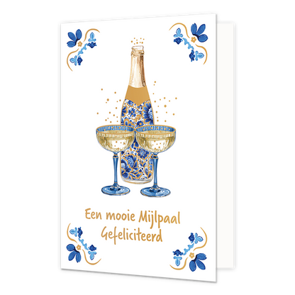 Een mooie mijlpaal gefeliciteerd - Formaat: Normaal - Vorm: Staand - Felicitatiekaart - Op deze wenskaart staat centraal een geopende fles champagne afgebeeld die gedecoreerd is met blauw-witte bloemmotieven in Delfts blauwe stijl, met daarvoor twee gevulde champagneglazen en omringende goudkleurige bubbels. De vier hoeken van de kaart bevatten symmetrische, traditionele tegeltjeswijsheid-achtige ornamenten in blauwe en goudkleurige tinten tegen een witte achtergrond. Onderaan de glazen staat in goudkleuri