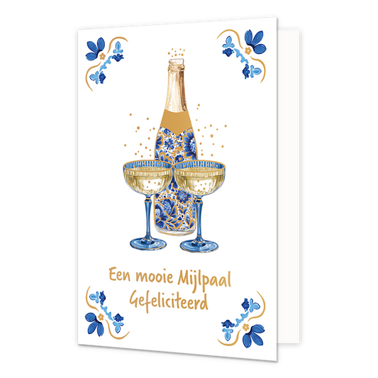 Een mooie mijlpaal gefeliciteerd - Formaat: Normaal - Vorm: Staand - Felicitatiekaart - Op deze wenskaart staat centraal een geopende fles champagne afgebeeld die gedecoreerd is met blauw-witte bloemmotieven in Delfts blauwe stijl, met daarvoor twee gevulde champagneglazen en omringende goudkleurige bubbels. De vier hoeken van de kaart bevatten symmetrische, traditionele tegeltjeswijsheid-achtige ornamenten in blauwe en goudkleurige tinten tegen een witte achtergrond. Onderaan de glazen staat in goudkleuri