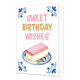 Sweet birthday wishes - Formaat: Normaal - Vorm: Staand - Verjaardagskaart - Op deze wenskaart staat aan de onderzijde een tompouce met een roze glazuurlaag afgebeeld op een gebaksbordje dat is versierd met blauw-witte bloemmotieven in Delfts blauwe stijl en gouden accenten. In de vier hoeken van de kaart bevindt zich een symmetrisch, traditioneel blauw met goudkleurig ornament tegen een witte achtergrond. Boven het gebakje staat in grote letters de tekst "Sweet Birthday Wishes" geschreven, waarbij de woor