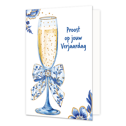 Proost op jouw verjaardag - Formaat: Normaal - Vorm: Staand - Verjaardagskaart - Op deze wenskaart staat aan de linkerzijde een gevuld champagneglas afgebeeld met een goudkleurige, bruisende inhoud en een grote strik om de steel die gedecoreerd is met blauw-witte bloemmotieven in Delfts blauwe stijl. De hoeken linksboven en rechtsonder zijn op een witte achtergrond versierd met bijpassende grote blauwe bloemen en bladeren met fijne goudkleurige randen. Aan de rechterzijde van het glas staat in blauwe lette