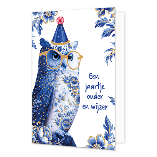Een jaartje ouder en wijzer - Formaat: Normaal - Vorm: Staand - Verjaardagskaart - Op deze wenskaart staat aan de linkerzijde een uil afgebeeld die gedecoreerd is met blauw-witte bloemmotieven in Delfts blauwe stijl, goudkleurige spikkels en een goudkleurige bril op zijn snavel draagt. Op de kop van de uil staat een blauw feestmutsje met een roze pompon, terwijl de hoeken van de kaart zijn versierd met grote blauwe bloemen en bladeren met gouden accenten tegen een witte achtergrond. Aan de rechterzijde van