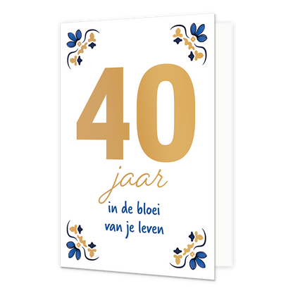 40 jaar - Formaat: Normaal - Vorm: Staand - Verjaardagskaart - Op deze wenskaart staat centraal het grote getal "40" in goudkleurige letters afgebeeld tegen een effen witte achtergrond. In de vier hoeken van de kaart bevindt zich een symmetrisch, traditioneel ornament in blauwe en goudkleurige tinten, geïnspireerd op een klassiek tegelontwerp. Onder het getal staat de handgeschreven tekst "jaar in de bloei van je leven", waarbij het woord "jaar" in het goud is gedrukt en de zin "in de bloei van je leven" i