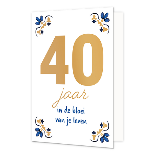 40 jaar - Formaat: Normaal - Vorm: Staand - Verjaardagskaart - Op deze wenskaart staat centraal het grote getal "40" in goudkleurige letters afgebeeld tegen een effen witte achtergrond. In de vier hoeken van de kaart bevindt zich een symmetrisch, traditioneel ornament in blauwe en goudkleurige tinten, geïnspireerd op een klassiek tegelontwerp. Onder het getal staat de handgeschreven tekst "jaar in de bloei van je leven", waarbij het woord "jaar" in het goud is gedrukt en de zin "in de bloei van je leven" i