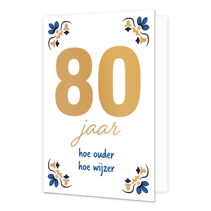 80 jaar - Formaat: Normaal - Vorm: Staand - Verjaardagskaart - Op deze wenskaart staat centraal het grote getal "80" in goudkleurige letters afgebeeld tegen een effen witte achtergrond. In de vier hoeken van de kaart bevindt zich een symmetrisch, traditioneel ornament in blauwe en goudkleurige tinten, geïnspireerd op een klassiek tegelontwerp. Onder het getal staat de handgeschreven tekst "jaar hoe ouder hoe wijzer", waarbij het woord "jaar" in het goud is gedrukt en de zin "hoe ouder hoe wijzer" in blauwe