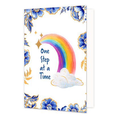 One step at a time - Formaat: Normaal - Vorm: Staand - Beterschapskaart - Op deze wenskaart staat centraal een kleurrijke regenboog afgebeeld die ontspringt uit een witte wolk met goudkleurige spikkels en omringd wordt door goudkleurige sterren. De hoeken en randen van de kaart zijn op een witte achtergrond rijkelijk versierd met grote blauwe bloemen en bladeren in Delfts blauwe stijl, afgewerkt met fijne goudkleurige details. Aan de linkerzijde van de regenboog staat in blauwe letters onder elkaar de teks