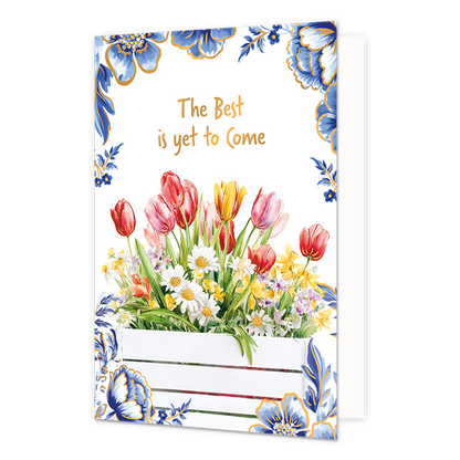 The best is yet to come - Formaat: Normaal - Vorm: Staand - Blanco kaart - Op deze wenskaart staat aan de onderzijde een witte houten plantenbak gevuld met een kleurrijk boeket van rode, roze en gele tulpen, witte madeliefjes en andere voorjaarsbloemen afgebeeld. De hoeken en randen van de kaart zijn op een witte achtergrond rijkelijk versierd met grote blauwe bloemen en bladeren in Delfts blauwe stijl met goudkleurige randen. Centraal aan de bovenzijde staat in goudkleurige letters onder elkaar de tekst "