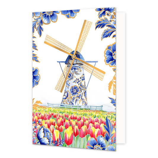 Molen - Formaat: Normaal - Vorm: Staand - Blanco kaart - Op deze wenskaart staat centraal een traditionele Nederlandse windmolen afgebeeld, waarvan de romp rijkelijk is gedecoreerd met blauw-witte bloemmotieven in Delfts blauwe stijl en de wieken goudkleurig zijn. De molen staat achter een laag wit hekje in een uitgestrekt veld vol met bloeiende rode en gele tulpen. De hoeken en randen van de kaart zijn tegen een witte achtergrond versierd met bijpassende grote blauwe bloemen en bladeren met fijne goudkleu