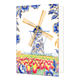 Molen - Formaat: Standaard - Vorm: Staand - Blanco kaart - Op deze wenskaart staat centraal een traditionele Nederlandse windmolen afgebeeld, waarvan de romp rijkelijk is gedecoreerd met blauw-witte bloemmotieven in Delfts blauwe stijl en de wieken goudkleurig zijn. De molen staat achter een laag wit hekje in een uitgestrekt veld vol met bloeiende rode en gele tulpen. De hoeken en randen van de kaart zijn tegen een witte achtergrond versierd met bijpassende grote blauwe bloemen en bladeren met fijne goudkl