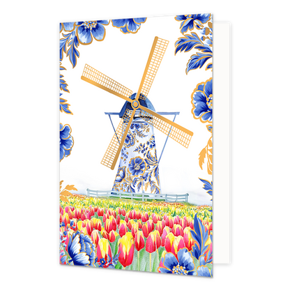 Op deze wenskaart staat centraal een traditionele Nederlandse windmolen afgebeeld, waarvan de romp rijkelijk is gedecoreerd met blauw-witte bloemmotieven in Delfts blauwe stijl en de wieken goudkleurig zijn. De molen staat achter een laag wit hekje in een uitgestrekt veld vol met bloeiende rode en gele tulpen. De hoeken en randen van de kaart zijn tegen een witte achtergrond versierd met bijpassende grote blauwe bloemen en bladeren met fijne goudkleurige randen.