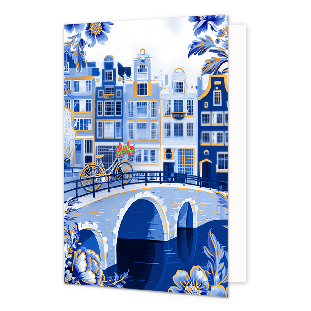 Op deze wenskaart is een sfeervol Nederlands stadsgezicht aan een gracht afgebeeld met karakteristieke grachtenpanden in blauwe en witte tinten met goudkleurige accenten. Op de stenen boogbrug over het water staat een fiets die is gedecoreerd met Delfts blauwe patronen en een mandje met rode tulpen aan het stuur. De hoeken en randen van de kaart zijn rijkelijk versierd met grote, gedetailleerde blauwe bloemen en bladeren met goudkleurige randen tegen een witte achtergrond.