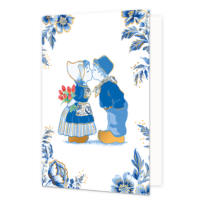  Op deze wenskaart staat een illustratie van een kussend jongetje en meisje in traditionele Nederlandse klederdracht, waarbij het meisje een boeket rode tulpen achter haar rug vasthoudt. De kinderen dragen blauwe kleding en goudkleurige klompen, wat aansluit bij de Delfts blauwe stijl van de omlijstende decoratie. De vier hoeken van de kaart zijn rijkelijk versierd met grote blauwe bloemen, bladeren en goudkleurige accenten tegen een witte achtergrond. Er bevindt zich geen tekst op deze illustratie. 