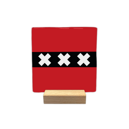 Amsterdam - Decoratie tegel - Formaat: - Op deze decoratie tegel staat een rood vlak met daarin een horizontale zwarte baan in het midden. Op deze zwarte baan zijn drie witte kruisen naast elkaar geplaatst. Dit ontwerp komt overeen met de vlag van Amsterdam. - Snelwenskaart