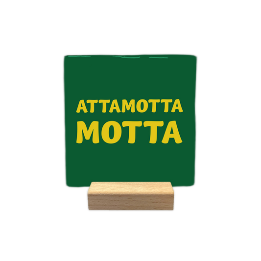 Attamotta motta - Decoratie tegel - Formaat: - Op deze decoratie tegel staat de tekst "attamotta motta" in gele letters centraal afgebeeld. De achtergrond van de tegel is donkergroen van kleur. - Snelwenskaart