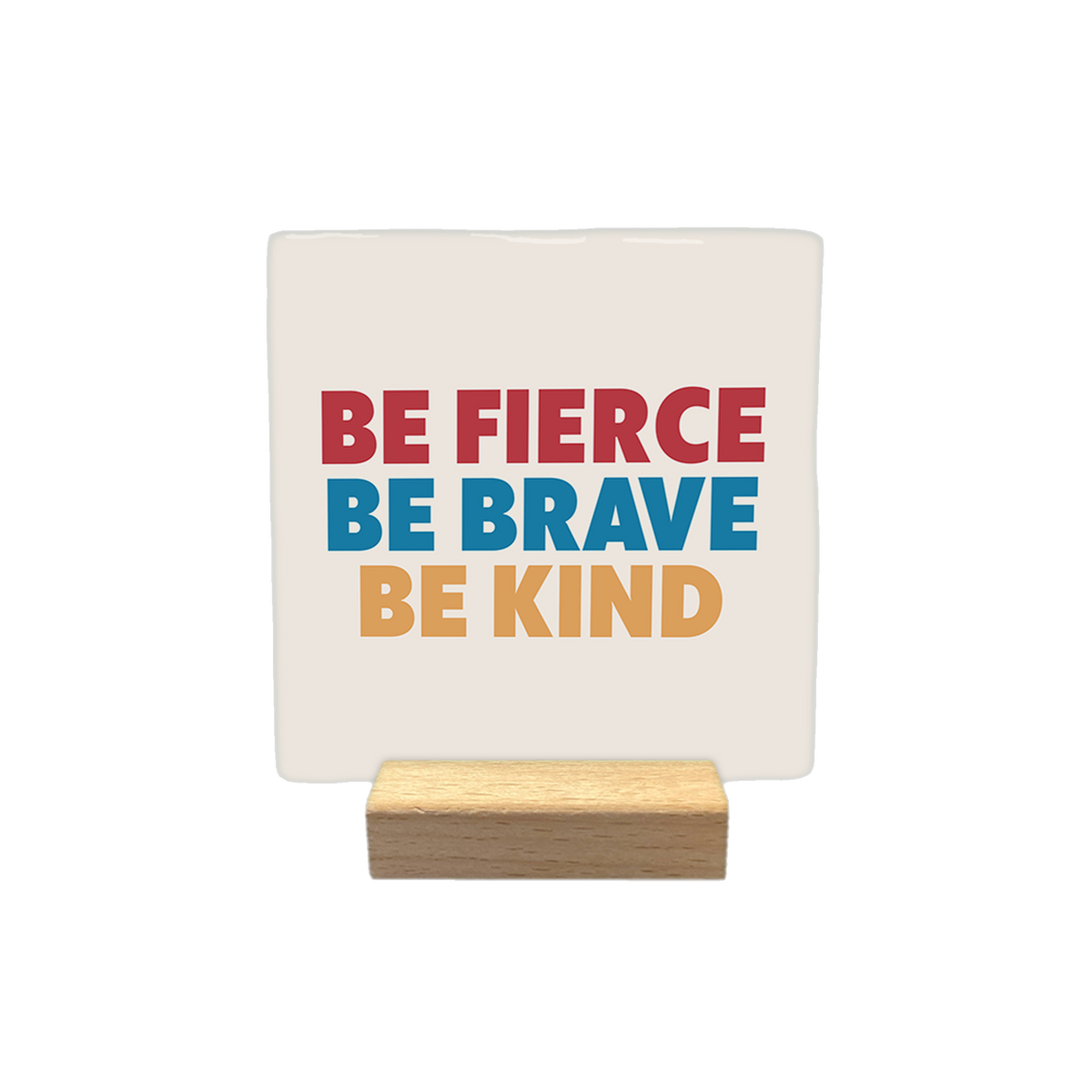 Be fierce be brave be kind - Decoratie tegel - Formaat: - Op deze decoratietegel staat de tekst "BE FIERCE", "BE BRAVE" en "BE KIND" onder elkaar in hoofdletters. De woorden zijn in drie verschillende kleuren uitgevoerd: de bovenste regel is rood, de middelste is blauw en de onderste is beige. De tekst is gecentreerd op een lichtbeige achtergrond. - Snelwenskaart