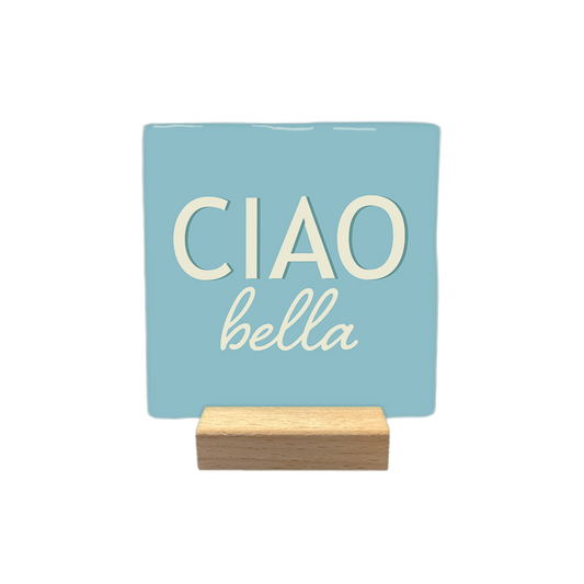 Ciao bella - Decoratie tegel - Formaat: - Op deze decoratietegel staat de tekst "CIAO" in grote, crèmekleurige hoofdletters met daaronder in kleinere, sierlijke letters "bella". Het ontwerp is gecentreerd op een lichtblauwe achtergrond - Snelwenskaart