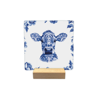 Delfts blauwe koe - Decoratie tegel - Formaat: - Op deze decoratie tegel staat de kop van een koe afgebeeld die volledig is versierd met een gedetailleerd Delfts blauw bloemmotief. De koe is omringd door een rand van dezelfde Delfts blauwe bloemen tegen een witte achtergrond. Het geheel is uitgevoerd in een klassieke blauw-witte kleurstelling. - Snelwenskaart