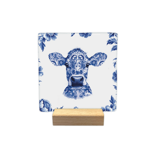 Delfts blauwe koe - Decoratie tegel - Formaat: - Op deze decoratie tegel staat de kop van een koe afgebeeld die volledig is versierd met een gedetailleerd Delfts blauw bloemmotief. De koe is omringd door een rand van dezelfde Delfts blauwe bloemen tegen een witte achtergrond. Het geheel is uitgevoerd in een klassieke blauw-witte kleurstelling. - Snelwenskaart