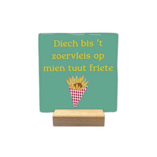 Diech bis 't zoervleis op mien tuut friete - Decoratie tegel - Formaat: - Op deze decoratie tegel staat een lichtgroene achtergrond met daarboven de gele tekst "Diech bis 't zoervleis op mien tuut friete". Onderaan is een afbeelding geplaatst van een rood-wit geblokt frietzakje gevuld met frietjes en een klodder bruine saus. Het ontwerp combineert een tekstuele uiting met een illustratie van een snack. - Snelwenskaart