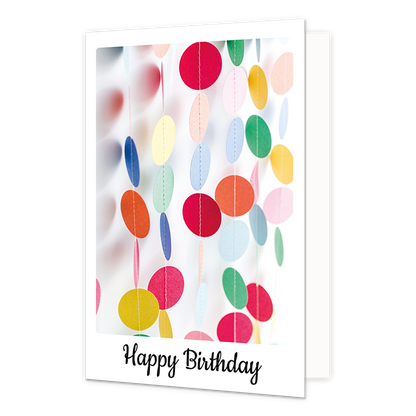 Happy birthday - Formaat: Klein - Vorm: Staand - Verjaardagskaart - Op deze wenskaart is een kleurrijke illustratie te zien van verticale slingers bestaande uit ronde, papieren schijfjes in diverse kleuren zoals rood, geel, blauw en groen. De achtergrond van de afbeelding is wit en helder, waarbij sommige slingers op de voorgrond scherp zijn en andere op de achtergrond vervaagd worden weergegeven. Onderaan de witte rand van de kaart staat in een zwart, sierlijk handschrift de tekst "Happy Birthday". De geh