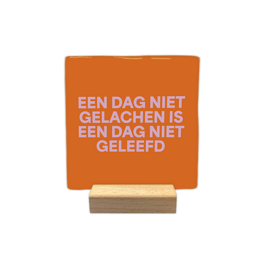 Een dag niet gelachen is een dag niet geleefd - Decoratie tegel - Formaat: - Op deze decoratie tegel staat de tekst "een dag niet gelachen is een dag niet geleefd" in vier regels afgebeeld. De tekst is geschreven in lichtroze letters. De achtergrond van de tegel heeft een oranje kleur. - Snelwenskaart