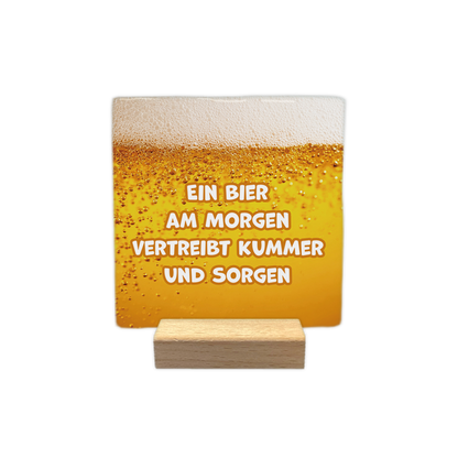 Ein bier am morgen - Decoratie tegel - Formaat: - Op deze decoratie tegel staat de tekst "bier is voor mij als een hartslag, ik kan niet zonder" in vijf regels afgebeeld. De tekst is geschreven in zwarte letters. De achtergrond van de tegel is wit en toont een illustratie van een geel bierglas met schuimkraag aan de linkerkant. - Snelwenskaart