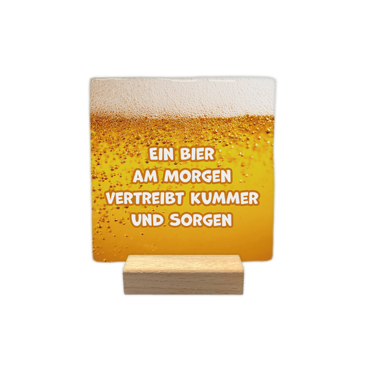 Ein bier am morgen - Decoratie tegel - Formaat: - Op deze decoratie tegel staat de tekst "bier is voor mij als een hartslag, ik kan niet zonder" in vijf regels afgebeeld. De tekst is geschreven in zwarte letters. De achtergrond van de tegel is wit en toont een illustratie van een geel bierglas met schuimkraag aan de linkerkant. - Snelwenskaart