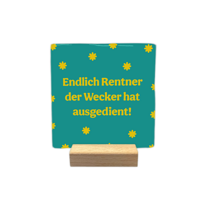 Endlicht Rentner - Decoratie tegel - Formaat: - Op deze decoratie tegel staat de tekst "endlich rentner der wecker hat ausgedient!" in gele letters afgebeeld. De achtergrond van de tegel is blauwgroen en is versierd met een patroon van kleine, gele sterretjes. - Snelwenskaart