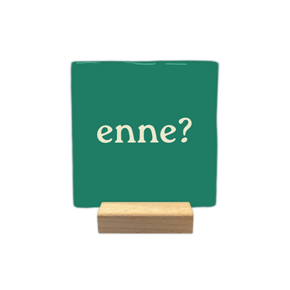 Enne? - Decoratie tegel - Formaat: - Op deze decoratie tegel staat de tekst "enne?" in crème-kleurige letters afgebeeld tegen een donkergroene achtergrond. Het ontwerp is minimalistisch en bevat geen verdere elementen of afbeeldingen. - Snelwenskaart