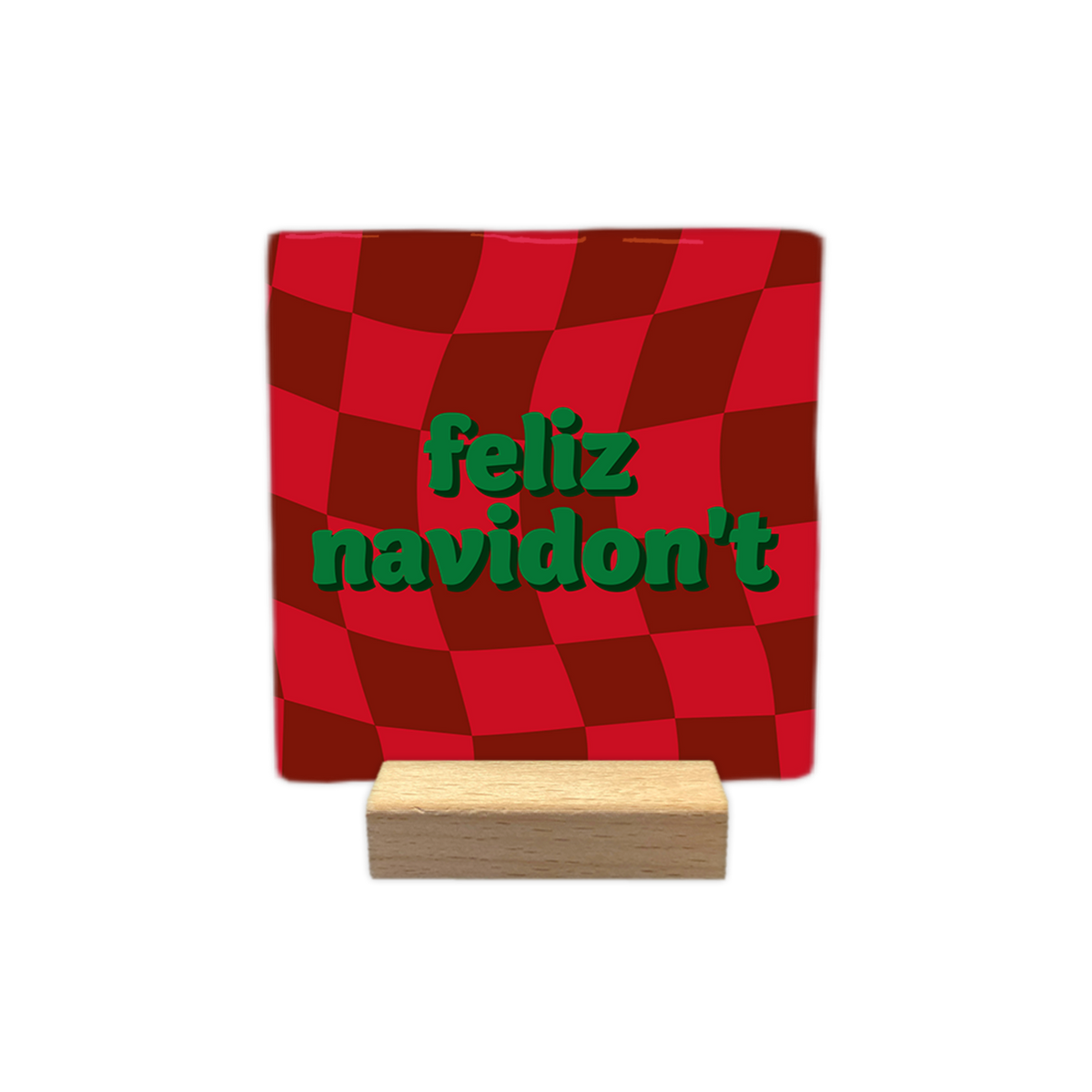 Feliz navidon't - Decoratie tegel - Formaat: - Op deze decoratie tegel staat een rood met donkerrood geblokt patroon dat een golvend effect heeft. In het midden staat de tekst feliz navidon't in groene letters gedrukt. - Snelwenskaart