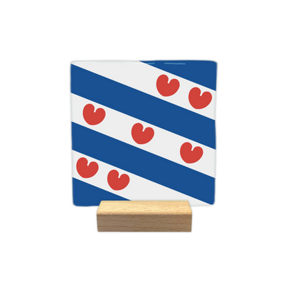 Friesland - Decoratie tegel - Formaat: - Op deze decoratie tegel staat een ontwerp met diagonale blauwe en witte banen. Over deze banen heen zijn zeven rode figuren geplaatst die de vorm hebben van bladeren of hartjes. Dit ontwerp is gebaseerd op de vlag van de provincie Friesland. - Snelwenskaart