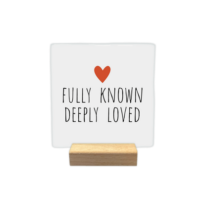 Fully known deeply loved - Decoratie tegel - Formaat: - Op deze decoratie tegel staat bovenaan een klein, oranje hartje afgebeeld. Daaronder staat in zwarte, handgeschreven letters de tekst "Fully known, deeply loved". Het ontwerp is geplaatst tegen een eenvoudige witte achtergrond. - Snelwenskaart