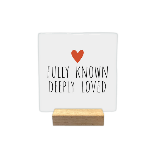 Fully known deeply loved - Decoratie tegel - Formaat: - Op deze decoratie tegel staat bovenaan een klein, oranje hartje afgebeeld. Daaronder staat in zwarte, handgeschreven letters de tekst "Fully known, deeply loved". Het ontwerp is geplaatst tegen een eenvoudige witte achtergrond. - Snelwenskaart