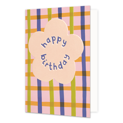 Happy birthday - Formaat: Normaal - Vorm: Staand - Verjaardagskaart - Op deze wenskaart staat in het midden een grote, lichtroze bloemvorm. Binnenin de bloem staat de tekst "happy birthday" in paarse, speelse letters die de ronde vorm van de bloem volgen. De achtergrond van de kaart bestaat uit een kleurrijk ruitpatroon met verticale en horizontale banen in de kleuren roze, geel, groen en paars. - Snelwenskaart