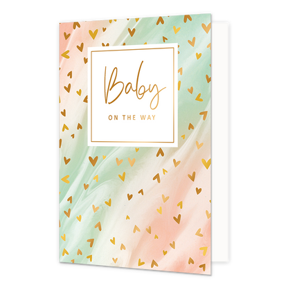 Baby on the way - Formaat: Normaal - Vorm: Staand - Zwanger kaart - Op deze artistieke wenskaart is een ontwerp te zien met de kleuren roze, beige en groen, waar kleine gouden hartjes op zitten. In het midden zit een wit blok met de gouden tekst "Baby on the way". - Snelwenskaart