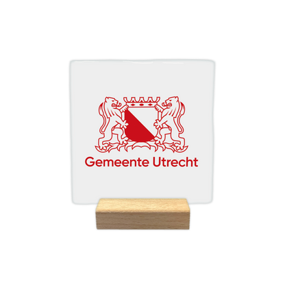 Gemeente Utrecht - Decoratie tegel - Formaat: - Op deze decoratie tegel staat het wapen van Utrecht afgebeeld in een rode kleur op een witte achtergrond. Het wapen wordt geflankeerd door twee leeuwen en bekroond met een kroon. Onder het wapen staat in rode letters de tekst "Gemeente Utrecht". Het geheel is in een strakke, minimalistische lijnstijl uitgevoerd. - Snelwenskaart