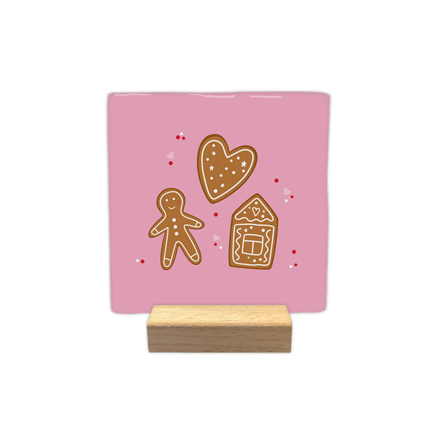 Gingerbread - Decoratie tegel - Op deze decoratietegel staat een illustratie van drie peperkoekfiguren tegen een lichtroze achtergrond: een hart, een peperkoekmannetje en een peperkoekhuisje, alle voorzien van witte decoratieve details. Rondom de figuren zijn kleine rode stippen en roze hartjes afgebeeld. - Snelwenskaart