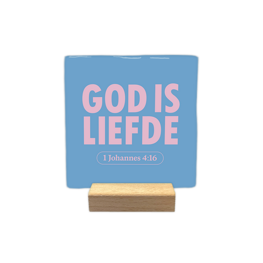 God is liefde - Decoratie tegel - Formaat: - Op deze decoratie tegel staat de tekst "god is liefde" in grote, roze letters centraal afgebeeld. Daaronder bevindt zich in een afgerond kader de tekst "1 johannes 4:16" in dezelfde kleur. Het geheel is geplaatst tegen een helderblauwe achtergrond. - Snelwenskaart